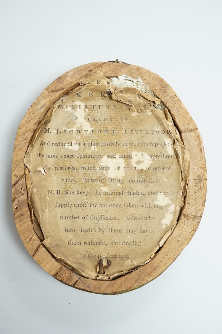 Mrs Mary Lightfoot (18th. C), oval painted silhouette portrait of a young lady, on plaster, printed trade label verso, embossed brass frame, overall 12cm high